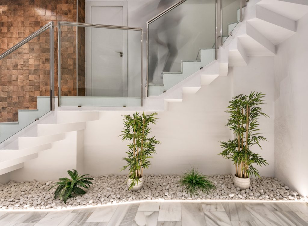 Escalera moderna con barandilla de cristal y jardineras decorativas.