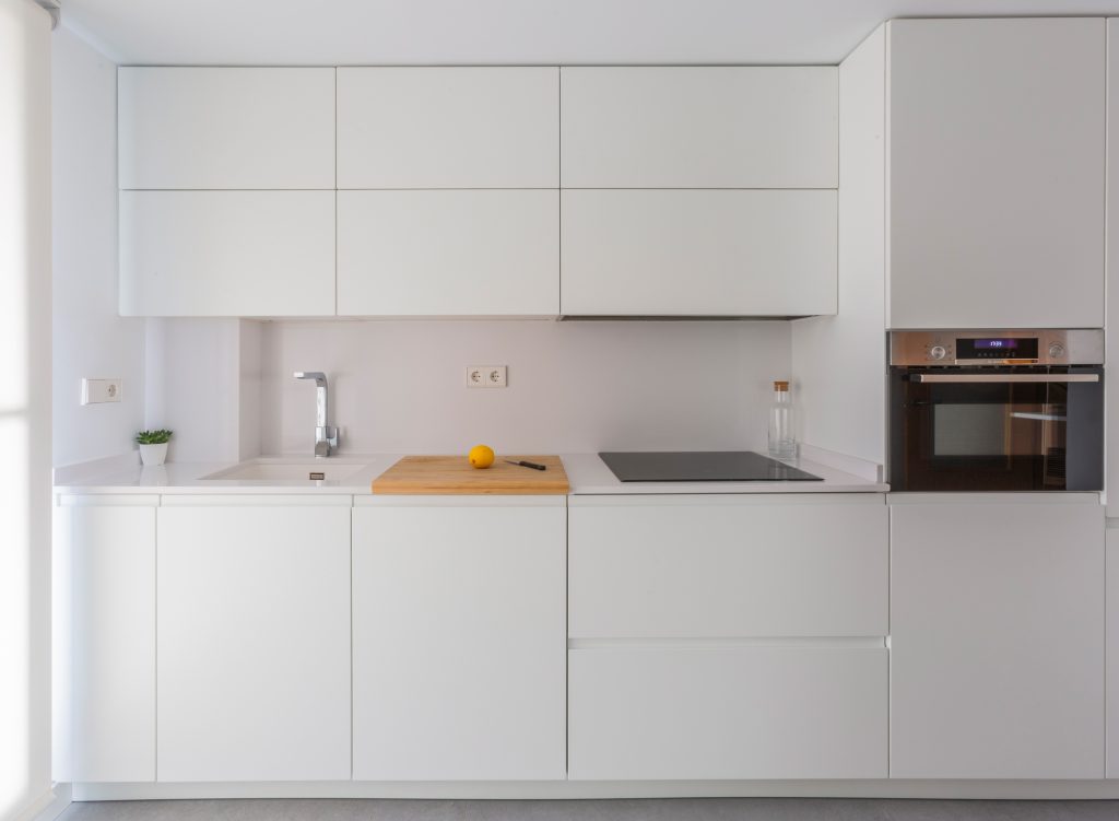 Cocina moderna con armarios blancos y encimera minimalista.