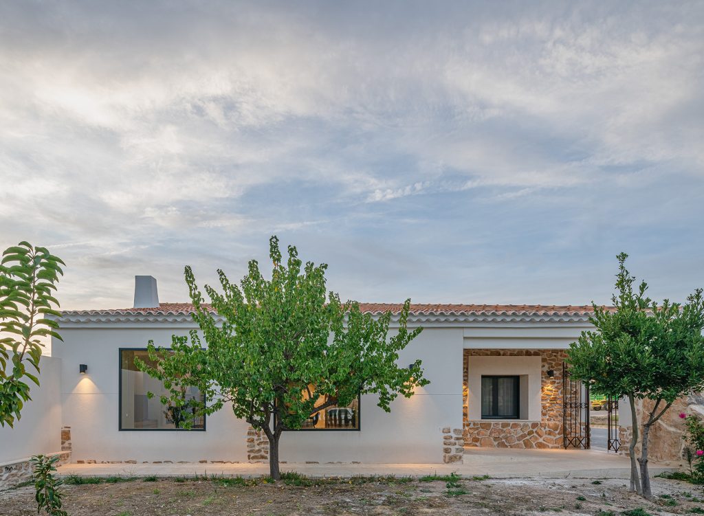 Casa de campo con fachada blanca y detalles de piedra.