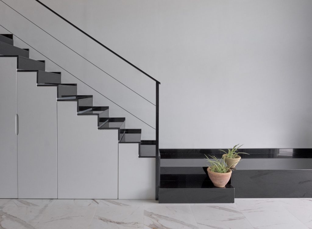 Escalera moderna con almacenamiento integrado y plantas decorativas.